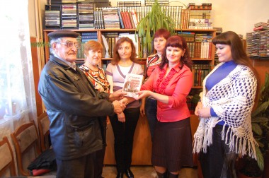 Леонид Иванович Дроздов передает экземпляр своей книги сотрудницам районной библиотеки